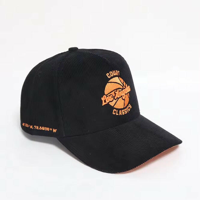 Angled view of black & orange corduroy snapback hat with embroidered Los Angeles logo and side coordinates – Court Classics 5-panel cap