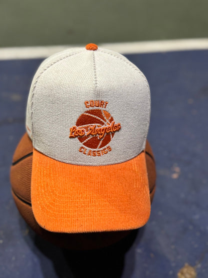 White & orange corduroy snapback hat resting on a basketball on the court – Court Classics